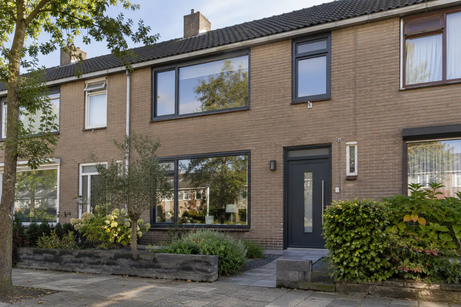 Rijtjeswoning met antraciet kunststof kozijnen en een antraciet voordeur